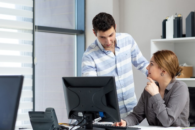 A front view young beautiful lady in grey shirt talking and discussing something with young man inside office during daytime building job activity