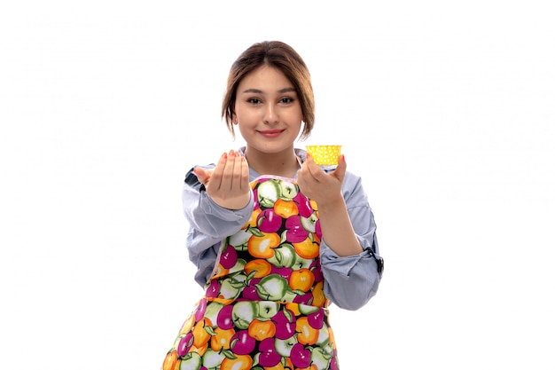 A front view young beautiful lady in light blue shirt and colorful cape holding yellow cake pans happy smiling expression