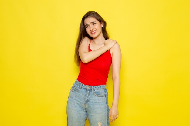 A front view young beautiful lady in red shirt and blue jeans having shoulder ache