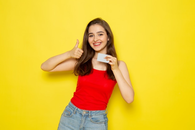 A front view young beautiful lady in red shirt and blue jeans holding white card