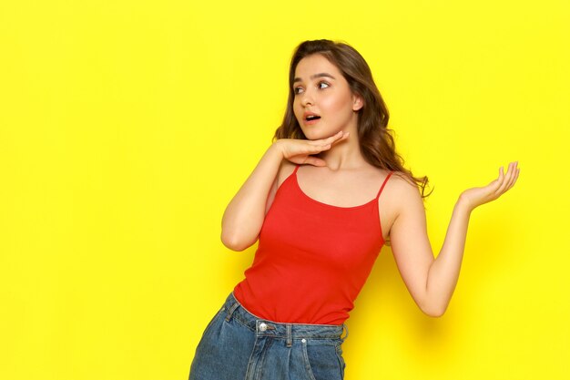 A front view young beautiful lady in red shirt and blue jeans posing with coquette expression