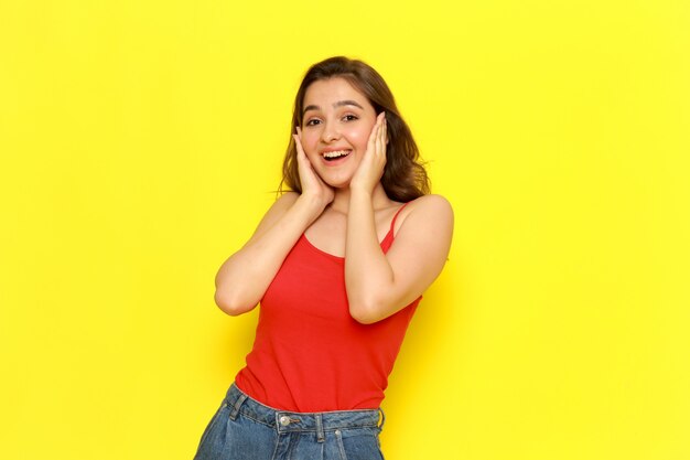 A front view young beautiful lady in red shirt and blue jeans posing with delighted and excited expression