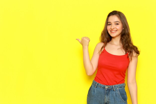 A front view young beautiful lady in red shirt and blue jeans posing with delighted excited expression