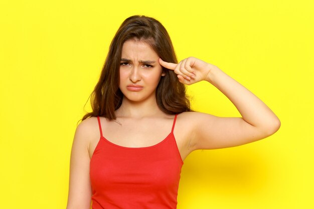 A front view young beautiful lady in red shirt and blue jeans posing with displeased expression