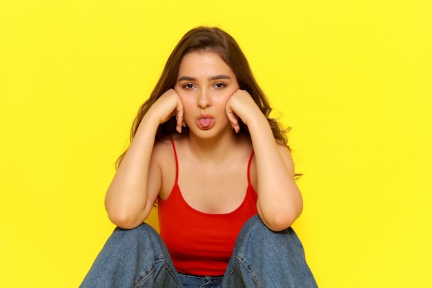 A front view young beautiful lady in red shirt and blue jeans posing with funny expression