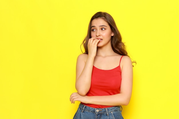 A front view young beautiful lady in red shirt and blue jeans posing with nevous expression