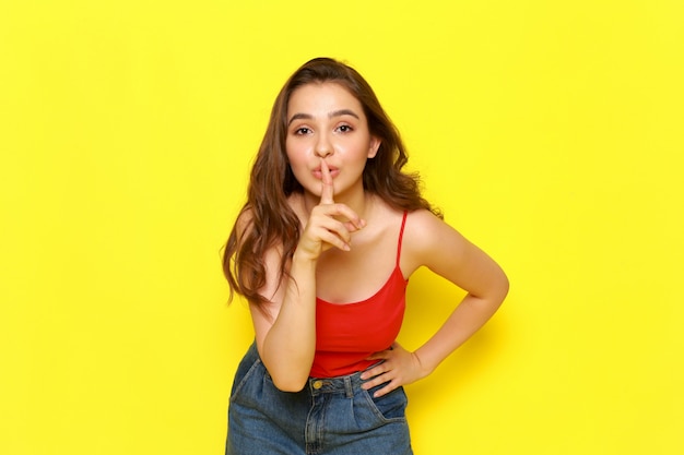 A front view young beautiful lady in red shirt and blue jeans posing with silence expression