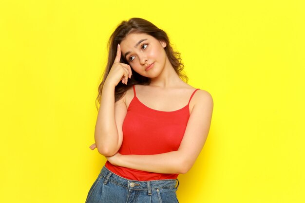 A front view young beautiful lady in red shirt and blue jeans posing with thinking expression