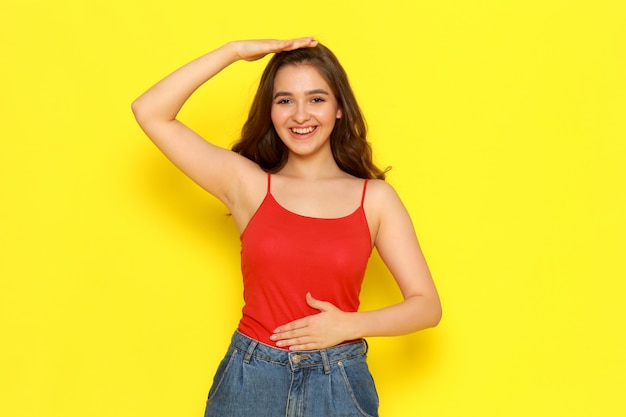 A front view young beautiful lady in red shirt and blue jeans smiling