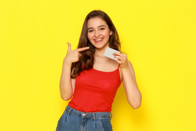 A front view young beautiful lady in red shirt and blue jeans smiling