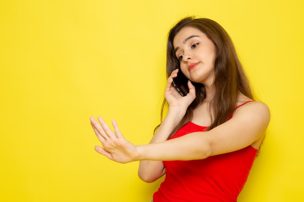 A front view young beautiful lady in red shirt and blue jeans talking on the phone