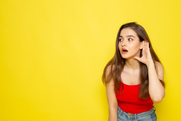 A front view young beautiful lady in red shirt and blue jeans trying to hear