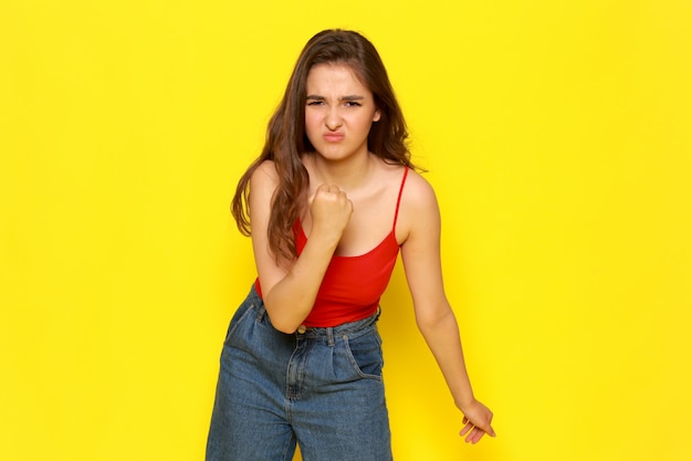 A front view young beautiful lady in red shirt and blue jeans with aggressive expression