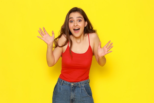 A front view young beautiful lady in red shirt and blue jeans with excited expression