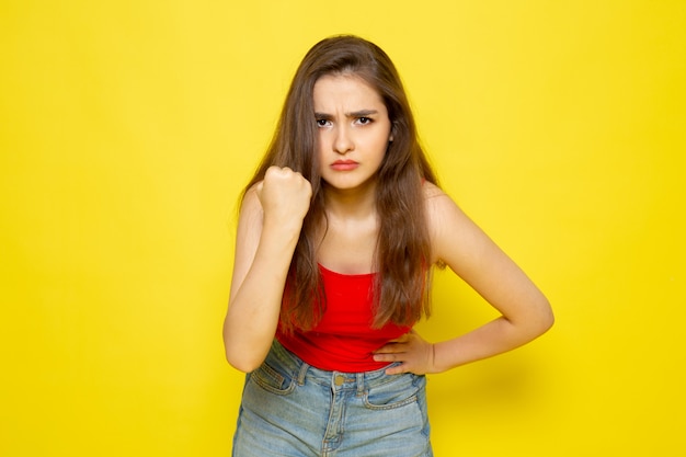A front view young beautiful lady in red shirt and blue jeans with threatenign expression