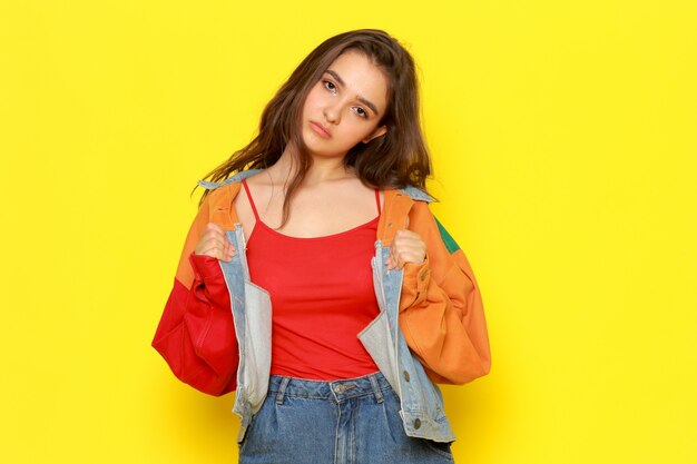 A front view young beautiful lady in red shirt coat and blue jeans with bored expression