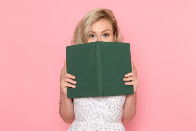 A front view young beautiful lady in white dress holding green copybook