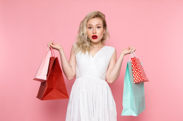 A front view young beautiful lady in white dress holding shopping packages