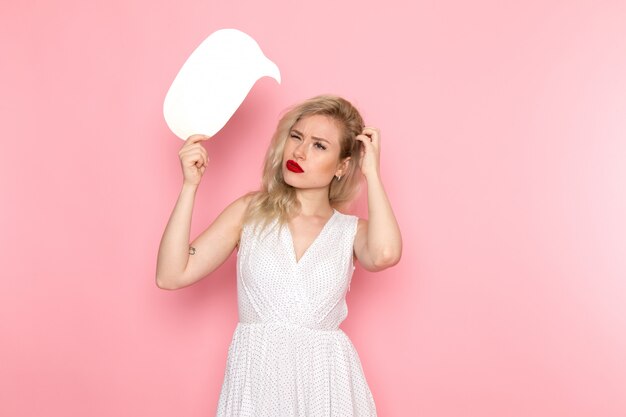 A front view young beautiful lady in white dress holding whit sign with confused expression