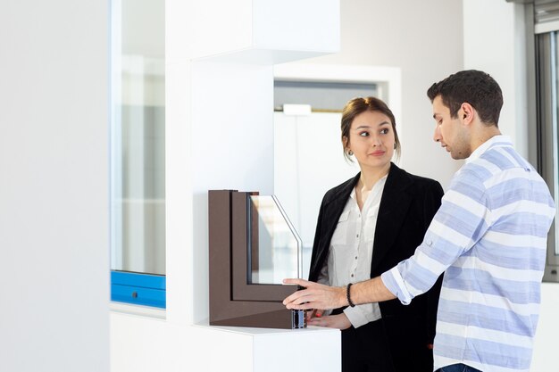 A front view young beautiful lady in white shirt dark jacket black trousers along with young man discussing something during daytime building job activity