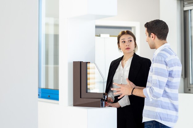 A front view young beautiful lady in white shirt dark jacket black trousers along with young man discussing something during daytime building job activity