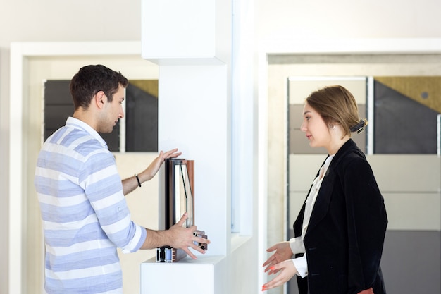 A front view young beautiful lady in white shirt dark jacket black trousers along with young man discussing work during daytime building job activity