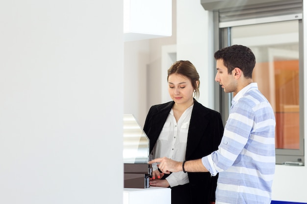 A front view young beautiful lady in white shirt dark jacket black trousers along with young man discussing work during daytime building job activity