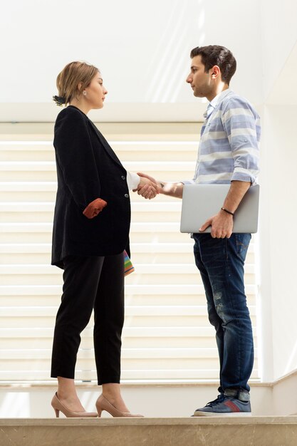 A front view young beautiful lady in white shirt dark jacket black trousers along with young man discussing work during daytime building job activity