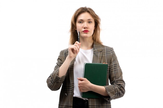 A front view young beautiful lady in white t-shirt black jeans and coat holding green book on the white