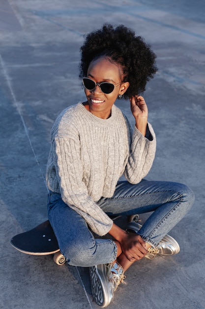 Free photo front view young beautiful woman sitting on a skateboard