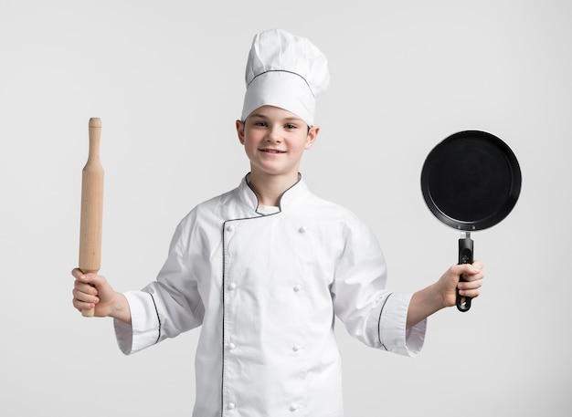 Front view young boy dressed up as chef holding tools