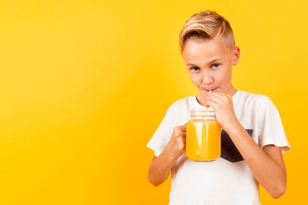 Front view young boy drinking orange fresh