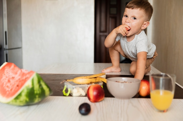 Вид спереди молодой мальчик ест фрукты