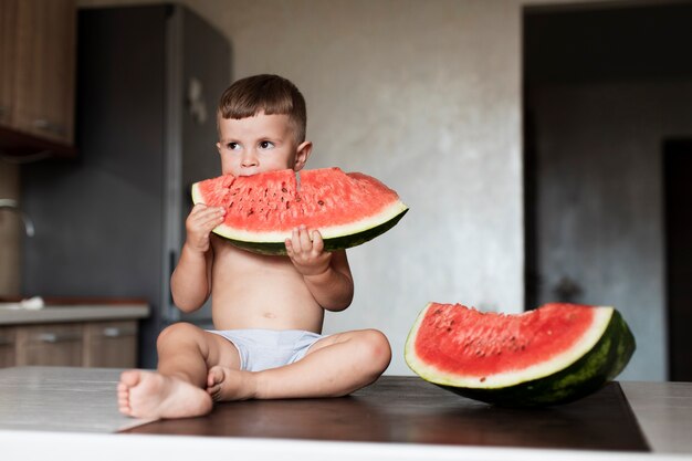 Free photo front view young boy eating watermelon