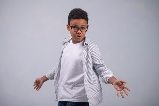 Front view of a young boy in glasses showing his open palms before the camera