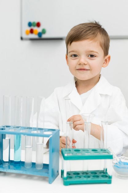 Front view of young boy scientist with test tubes and lab coat