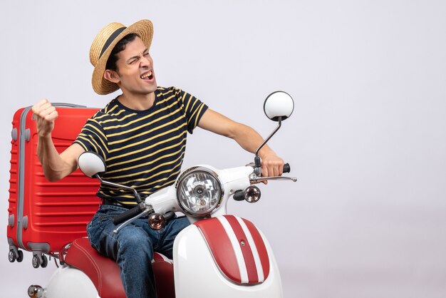 Front view of young boy with straw on moped showing winning gesture