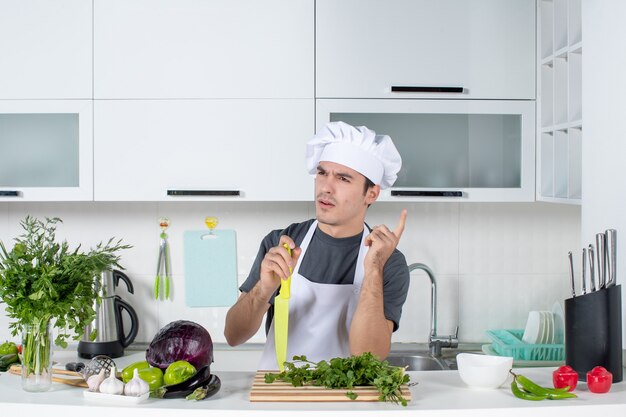 Front view young chef in confusion holding knife