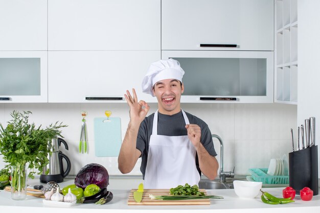 제복을 입은 젊은 요리사가 혀를 내밀고 있는 오키 사인을 하고 있다