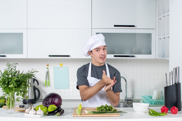 Front view young chef in uniform making special hand gesture