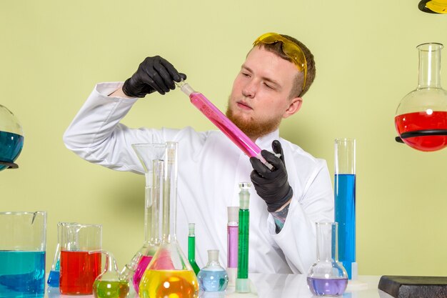 Front view young chemist looking at pink chemical tube