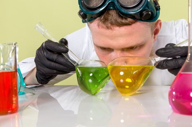 Foto gratuita giovane chimico di vista frontale che prova a differenziare i prodotti chimici verdi e gialli