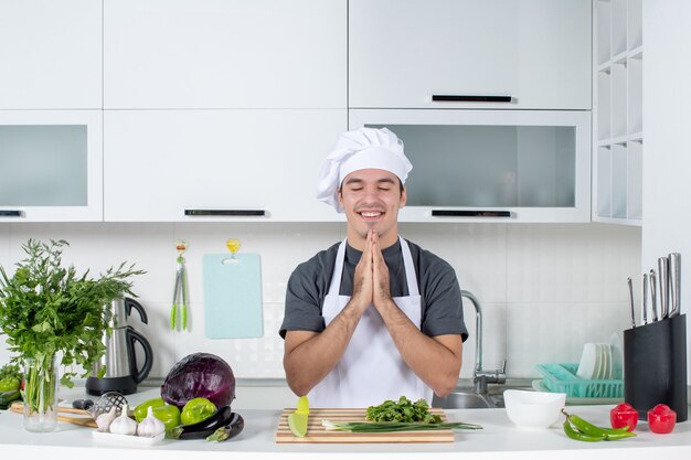 전면 보기 젊은 요리사 제복을 입은 손을 함께 감고 눈을 결합