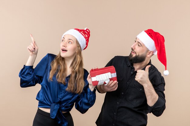 Front view young couple both holding males present on pink desk gift holiday photo new year christmas