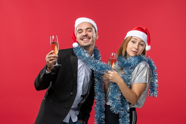 Бесплатное фото Вид спереди молодая пара празднует новый год на красной стене любит рождественский цвет