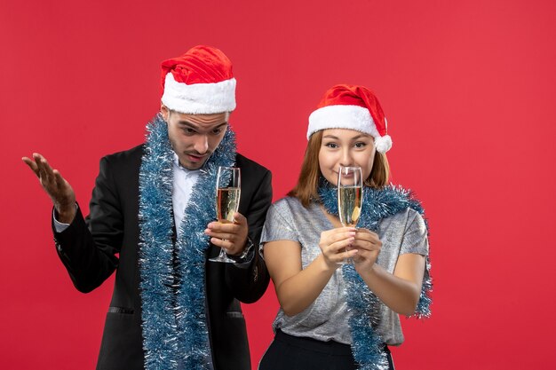 赤い机の上の新年を祝う正面図の若いカップルクリスマスパーティー飲み物愛