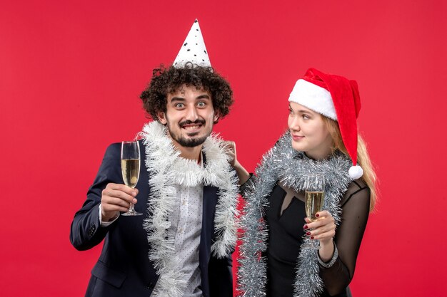 Front view young couple celebrating new year on a red wall holiday love christmas party