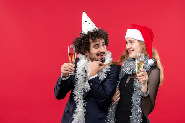 Вид спереди молодая пара празднует новый год на красной стене праздник любви рождественская вечеринка