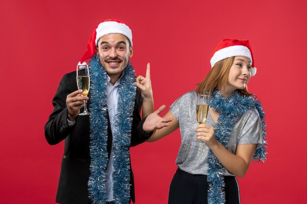 Free photo front view young couple celebrating new year on red wall love christmas color holiday
