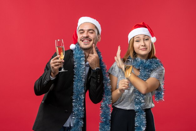 赤い壁の愛のクリスマスの色で新年を祝う正面図の若いカップル